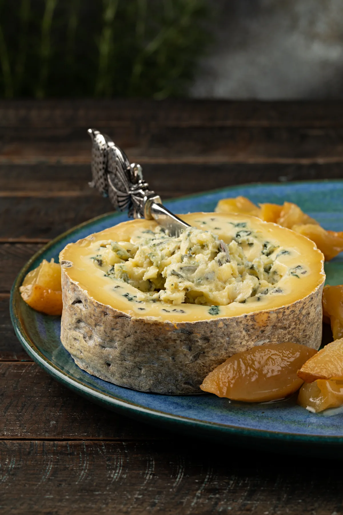 Gorgonzola de colher aberto no topo, com a colher dentro, e compota de peras ao redor